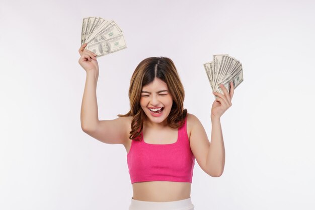 Retrato de una joven emocionada sosteniendo un montón de billetes de dólares aislados sobre fondo blanco