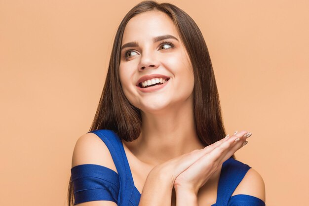 El retrato de la joven con emociones felices sobre fondo marrón de estudio