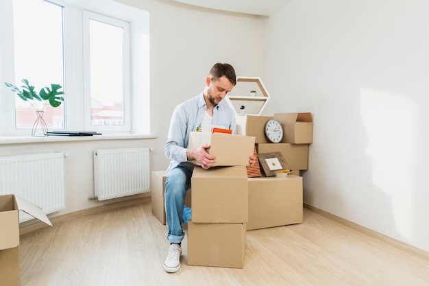 Retrato de un joven empacando las cajas de cartón en casa.