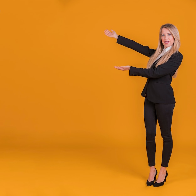Retrato de una joven empresaria dando presentación contra un fondo naranja