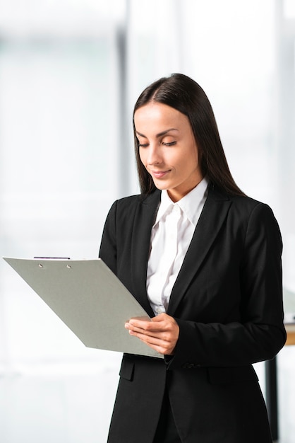 Retrato de una joven empresaria mirando portapapeles