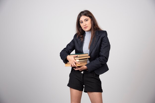 Retrato de joven empresaria sosteniendo una pila de libros.