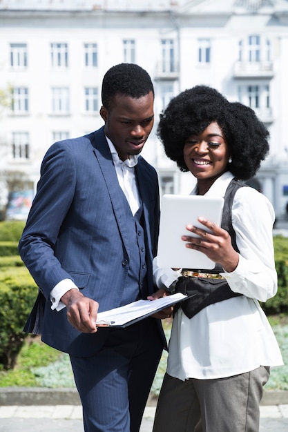 Foto gratuita retrato de un joven empresario africano y empresaria mirando tableta digital