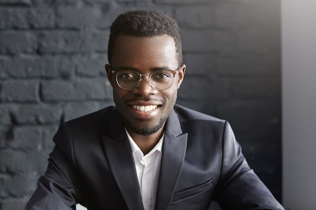 Foto gratuita retrato de joven empresario afroamericano confiado y exitoso con gafas elegantes