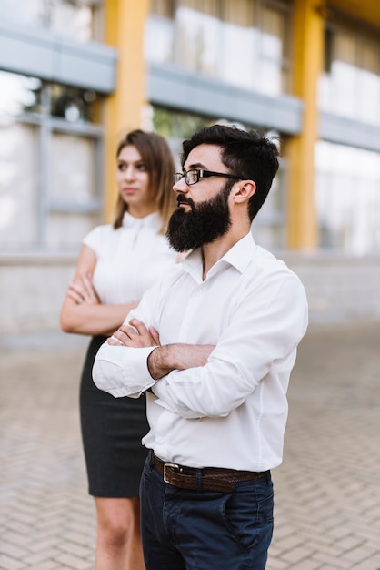 Retrato de joven empresario y empresaria de pie con el brazo cruzado