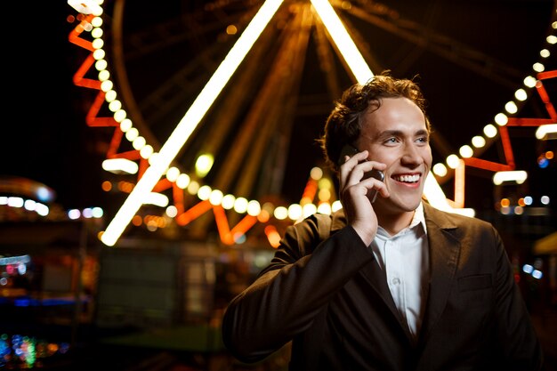 Retrato de joven empresario exitoso sobre el parque de atracciones nocturno. DOF superficial