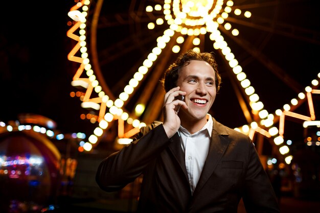 Retrato de joven empresario exitoso sobre el parque de atracciones nocturno. DOF superficial