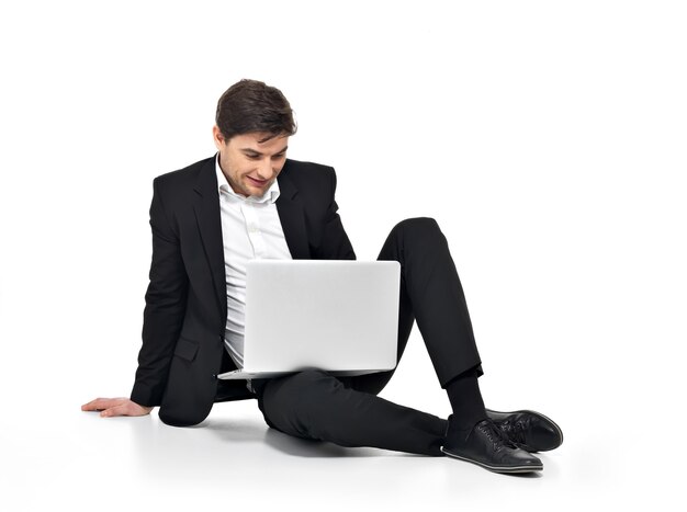 Retrato de joven empresario feliz trabajando en equipo portátil aislado en blanco.