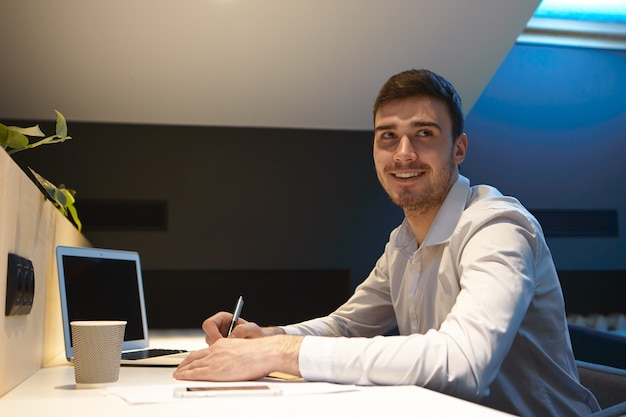 Retrato de joven empresario guapo con rastrojo mirando a otro lado con sonrisa satisfecha