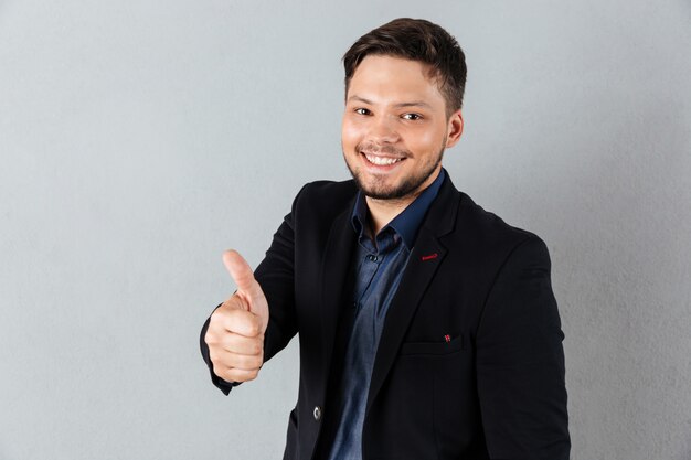 Retrato de un joven empresario mostrando pulgares arriba gesto