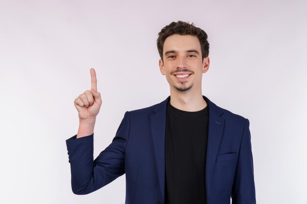 Retrato de joven empresario señalando con el dedo el espacio de copia aislado sobre fondo blanco de estudio