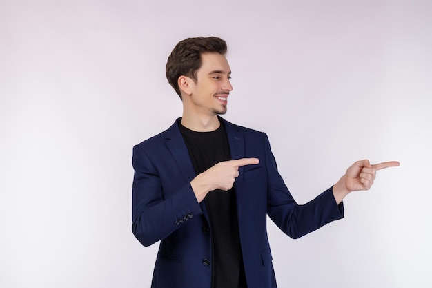 Retrato de joven empresario señalando con el dedo el espacio de copia aislado sobre fondo blanco de estudio