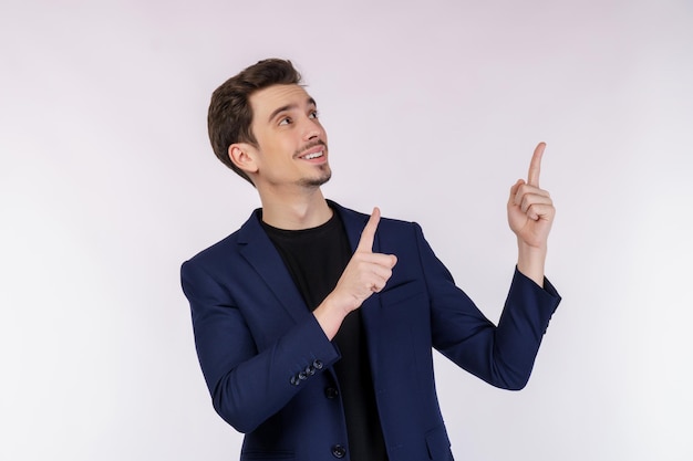 Retrato de joven empresario señalando con el dedo el espacio de copia aislado sobre fondo blanco de estudio