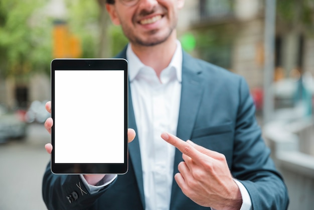 Retrato de un joven empresario sonriente apuntando su dedo hacia la tableta digital