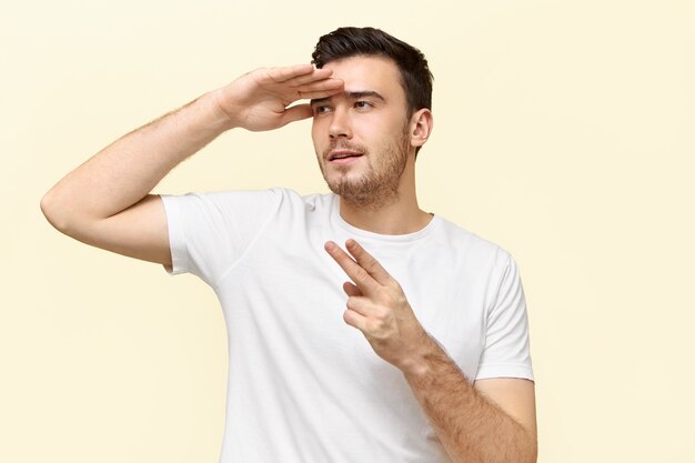 Retrato de joven enérgico activo divirtiéndose haciendo gestos como si estuviera sosteniendo una pistola