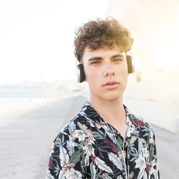 Retrato de un joven escuchando música en auriculares