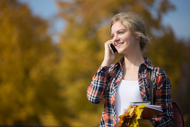 Retrato de joven estudiante atractivo outsides, hablando por su teléfono