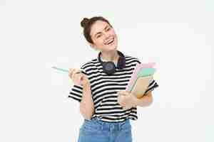 Foto gratuita retrato de una joven estudiante con cuadernos y auriculares en el cuello posando para la universidad