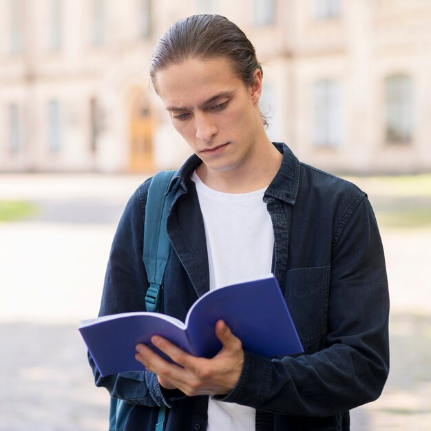 Retrato de joven estudiante masculino leyendo