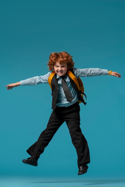 Retrato de joven estudiante en uniforme escolar saltando en el aire