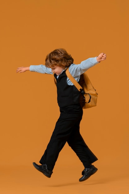 Retrato de joven estudiante en uniforme escolar saltando en el aire