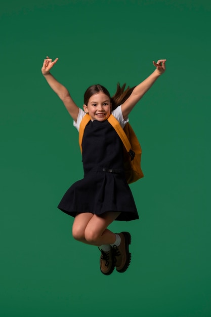 Retrato de una joven estudiante con uniforme escolar saltando en el aire