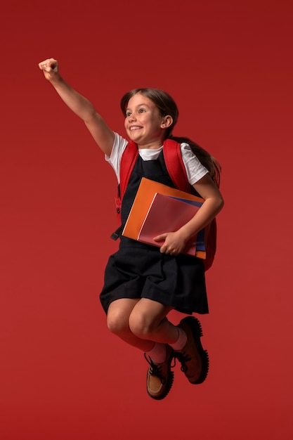 Retrato de una joven estudiante con uniforme escolar saltando en el aire