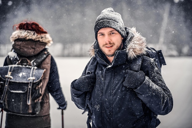 Retrato de un joven excursionista con una mochila caminando con su novia por un bosque de invierno