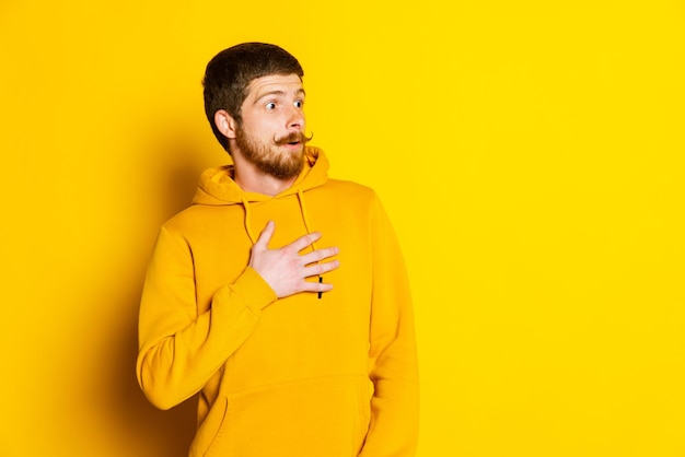 Retrato de un joven con una expresión facial sorprendida posando aislado sobre un fondo amarillo