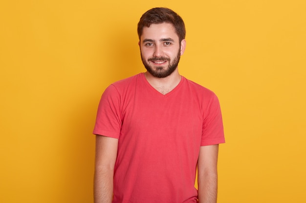 Retrato de joven feliz atractivo barbudo, guapo hombre vestido con camiseta casual roja, sonriendo