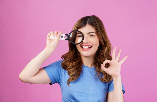 Retrato de una joven feliz con una camiseta informal que muestra una buena opción de solución de anuncios oksign aislada sobre un fondo rosa