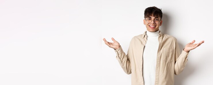 Foto gratuito retrato de un joven feliz y complacido extendió las manos hacia los lados y sonrió amigablemente satisfecho