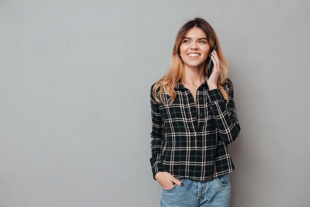 Retrato de una joven feliz hablando por teléfono móvil