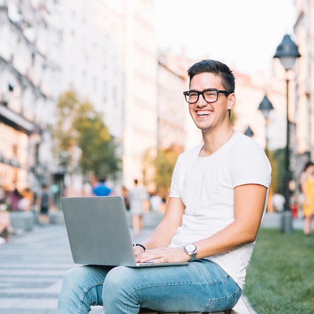 Foto gratuita retrato de un joven feliz con portátil