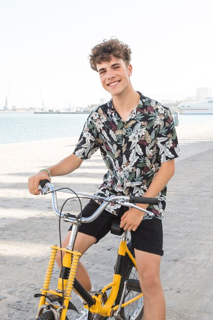 Retrato de un joven feliz sentado en bicicleta