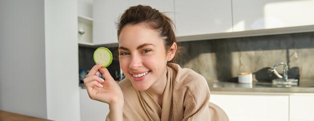 Retrato de una joven feliz y sonriente en la cocina cocinando picando calabacines sosteniendo verduras