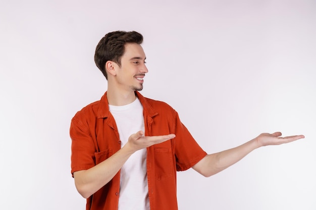 Retrato de un joven feliz y sonriente que presenta y muestra su texto o producto aislado de fondo blanco