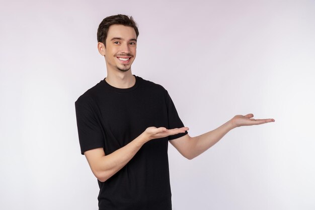 Retrato de un joven feliz y sonriente que presenta y muestra su texto o producto aislado de fondo blanco