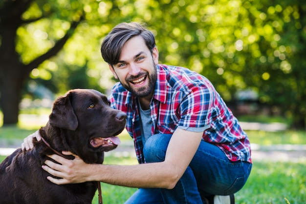 Retrato de un joven feliz con su perro en el parque