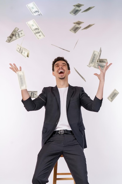 Retrato de un joven feliz tirando dinero mientras está de pie en un fondo aislado