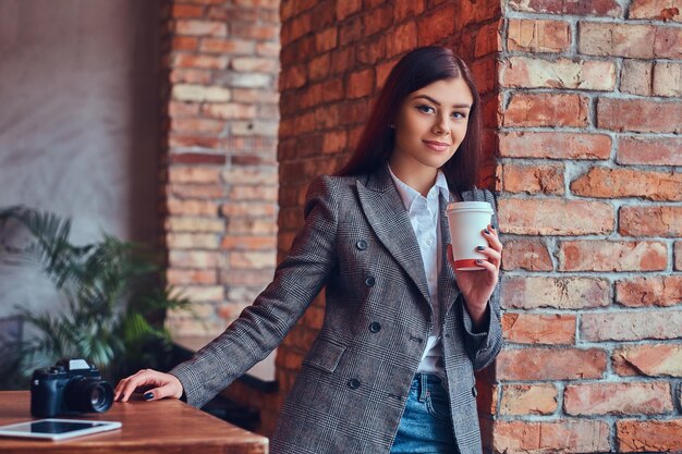 Retrato de una joven fotógrafa sostiene una taza de una mañana