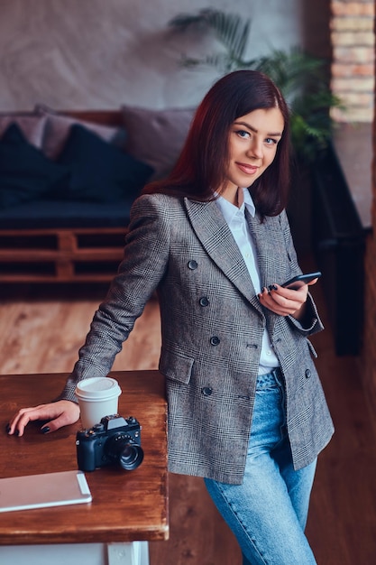 Retrato de una joven fotógrafa trabaja con un teléfono leani