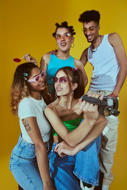 Retrato de un joven grupo de amigos al estilo de la moda de los años 2000 posando con cámara