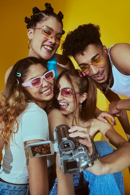 Retrato de un joven grupo de amigos al estilo de la moda de los años 2000 posando con cámara