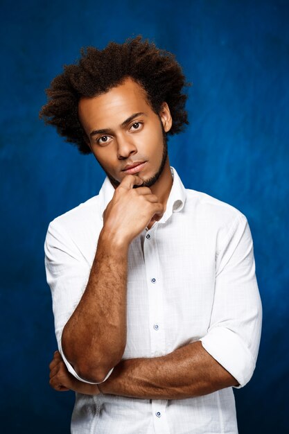 Retrato de joven guapo africano sobre pared azul.