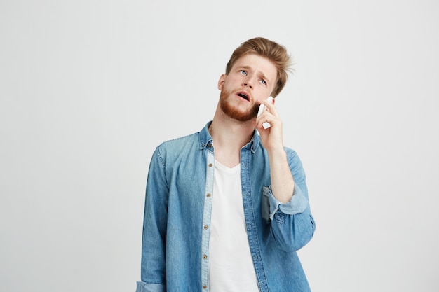 Retrato de joven guapo con barba hablando por teléfono.