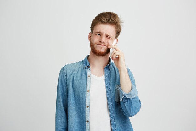 Retrato de joven guapo con barba no está de acuerdo hablando por teléfono.