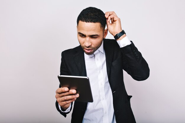 Retrato joven guapo con camisa blanca y chaqueta negra en el trabajo con tableta. Hombre de negocios de moda, malentendido, ocupado, exitoso, estilo de vida moderno.