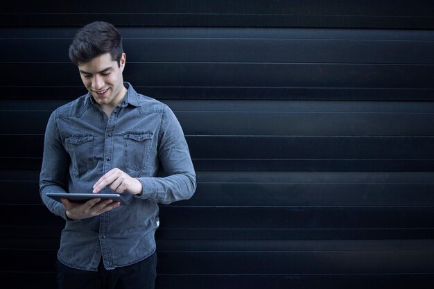 Retrato de joven guapo escribiendo en la computadora de la tableta y navegar por internet