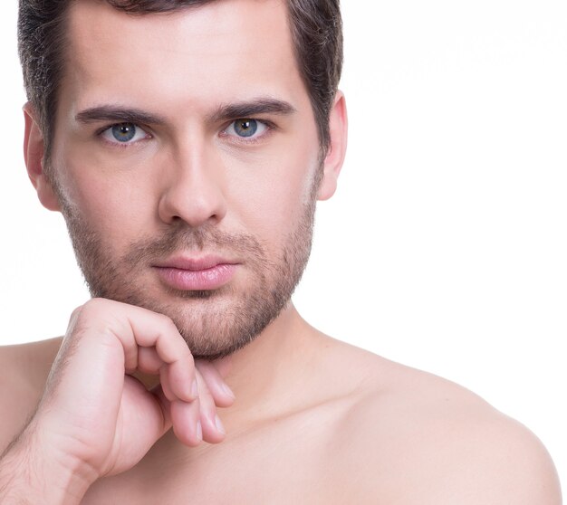 Retrato de joven guapo con la mano cerca de la cara en la pared blanca.